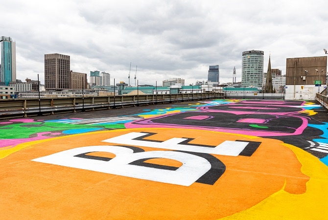 Be Bold artwork painted in white on a yellow and orange background on a rooftop