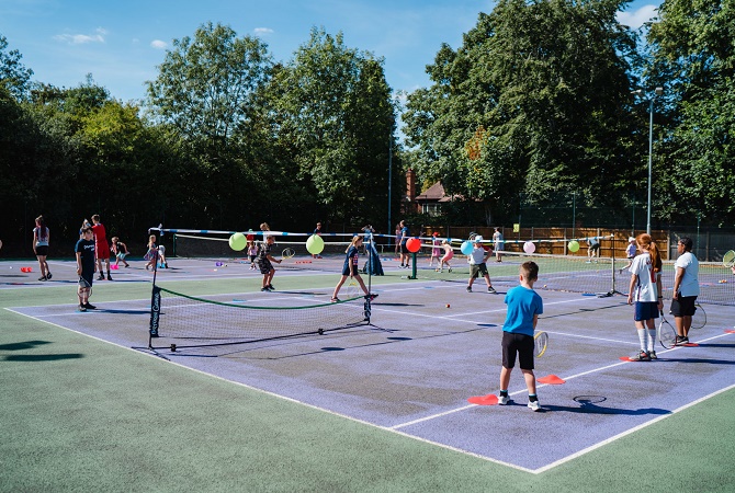 Group of children playing tennis on a number of tennis courts