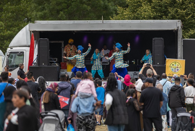 Group of dancers perform on a stage in front of a crowd of people