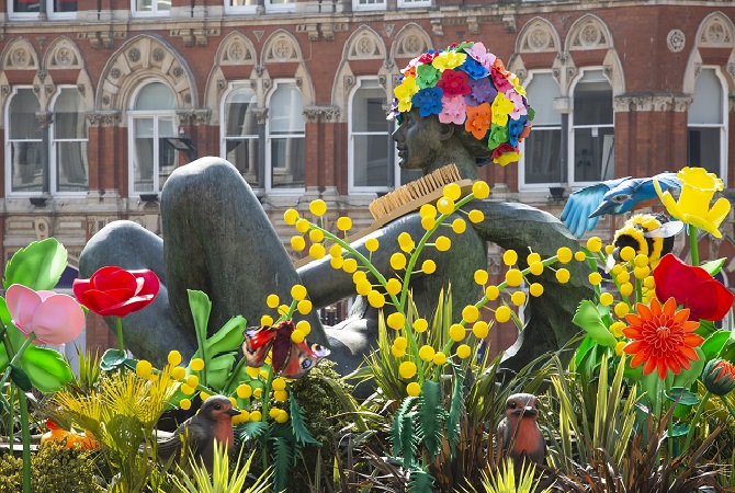 Vibrant scene of people in bright colours surrounding the Floozie statue in Victoria Square