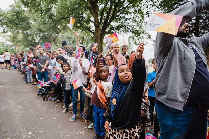 Local residents lining the Queen's Baton Route and waving Commonwealth Games flags