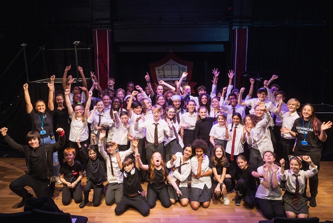 A large group of children stood together celebrating on stage