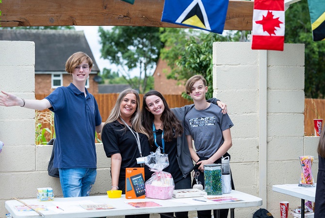 Four people stood behind a table at a community garden fete. Commonwealth flag bunting is in the foreground