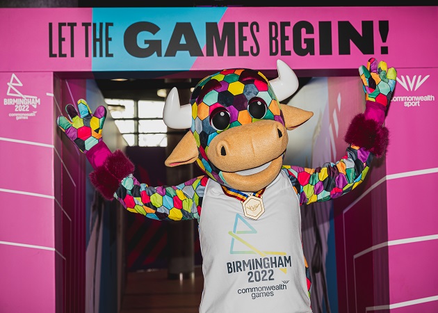 Commonwealth games mascot arms raised under a sign saying, Let the games begin!