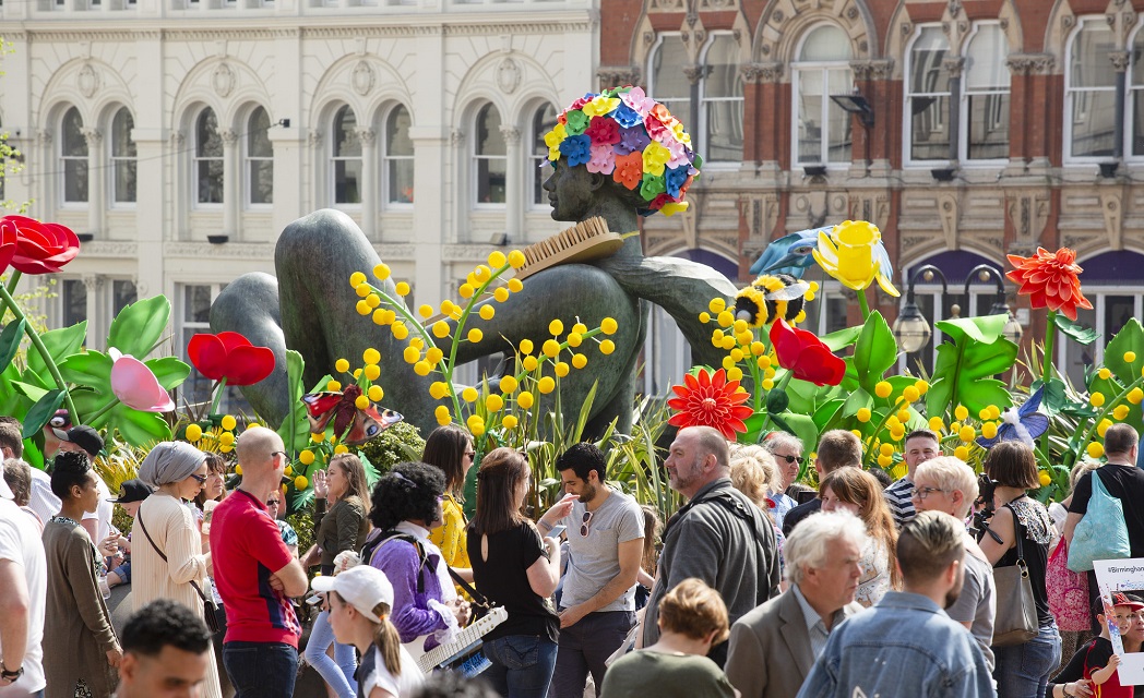 Vibrant scene of people in bright colours surrounding the Floozie statue in Victoria Square