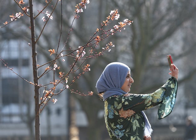 A lady taking a selfie by the new temporary blossom garden in Birmingham city centre