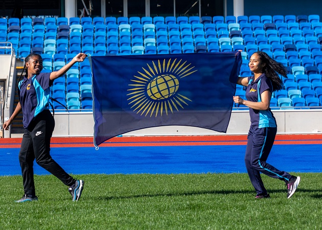 Two school children carry the Commonwealth flag at the Alexander Stadium on Commonwealth Day