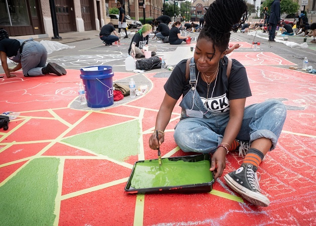 Young people sitting on the floor and painting the pavement