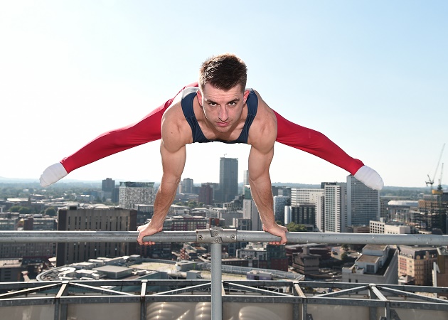 Max Whitlock, British gymnast, doing a balance move on metal bars above the Rotunda