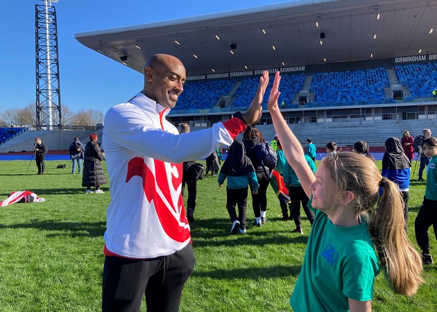 Team England triple jumper Nathan Douglas high fives a pupil from Hillstone Primary School in Shard End at the Alexander Stadium